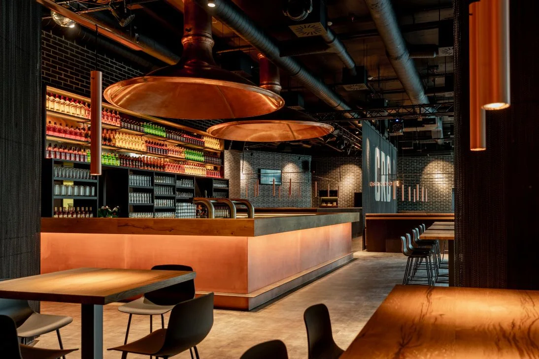 Gastraum des Classic Rock Café mit Bar, kupfernen Leuchten und Holztischen