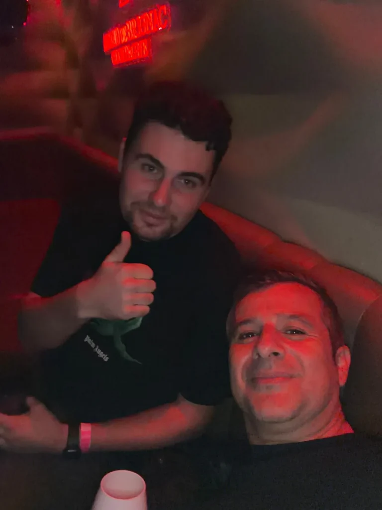 Selfie von zwei Männern im Club in rotem Licht, einer zeigt den Daumen hoch