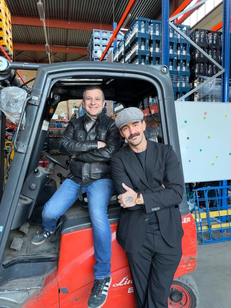 Die beiden Gastgeber an einem roten Gabelstapler in einem Getränkelager